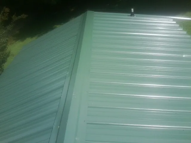 New green metal panels meeting at the ridge of a roof — Flat Roof Repair work by our crew in Bourbon