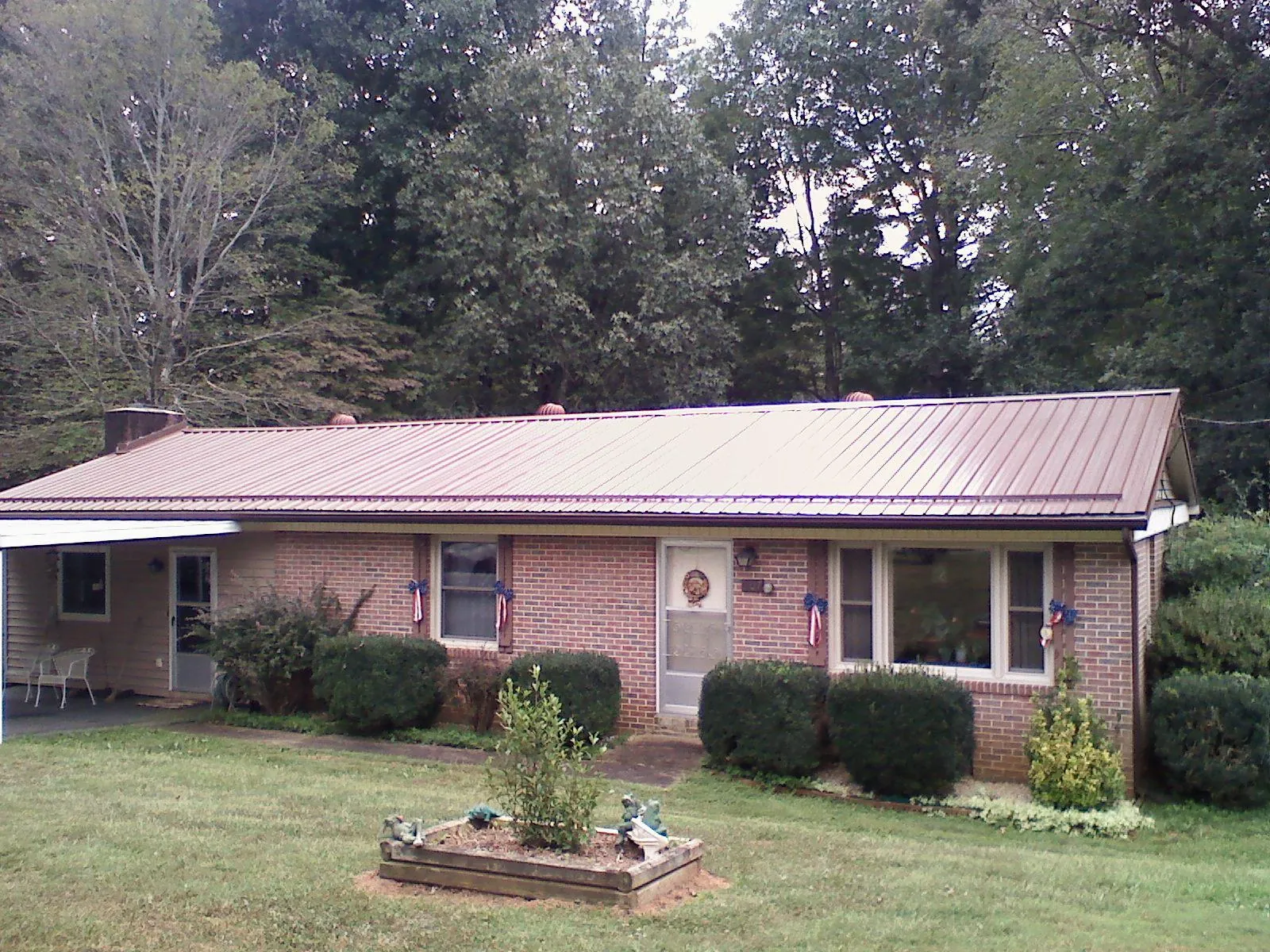 Bronze metal roof on a brick ranch home with a carport in Bourbon
