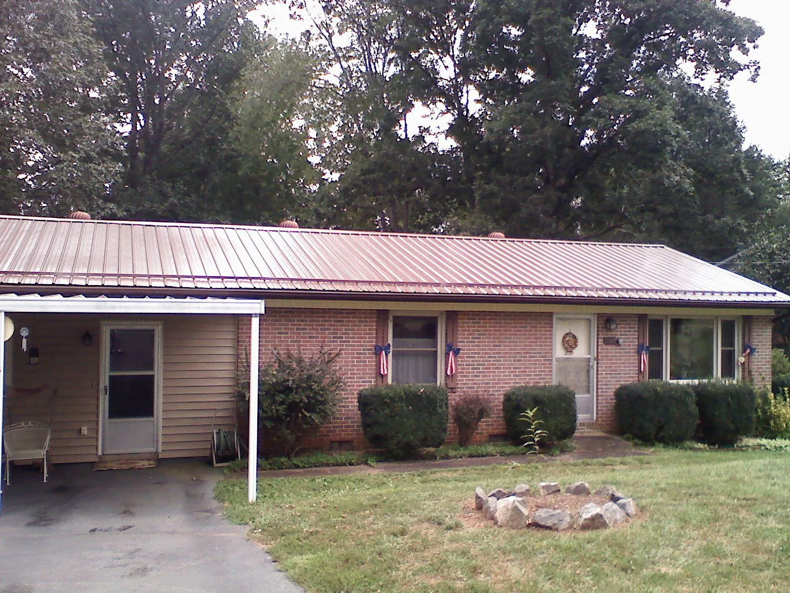 Bronze metal roof and carport on a brick ranch home — Roof Repair work by our crew in Bourbon