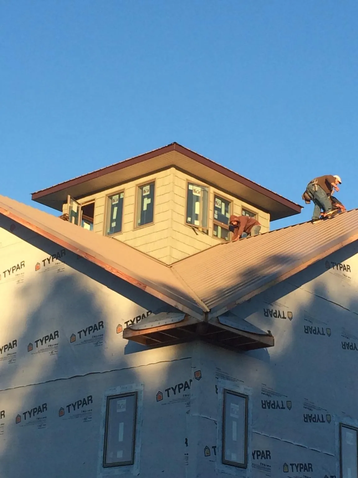 Roofers working around a rooftop cupola on a new metal roof at sunset — Roof Waterproofing in Bourbon by Roofing Brothers